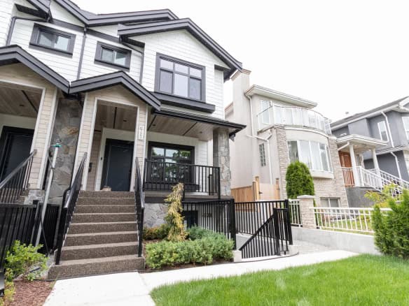 Modern multi-level residential home with contemporary exterior design, featuring stone accents, black railings, and a lush front lawn, showcasing prime Vancouver real estate listings on Orca Realty Inc.