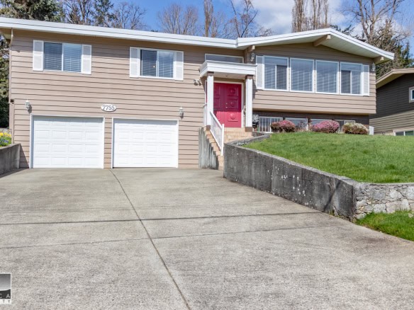 Bright multi-level family home with double garage, pink front door, landscaped front yard, and spacious driveway in a quiet neighbourhood. Perfect for Vancouver Island real estate buyers.