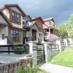 Colorful modern multi-family homes along a sloped street in a vibrant neighbourhood in Vancouver, BC, showcasing contemporary architecture and lush greenery, perfect for real estate investment or family living.