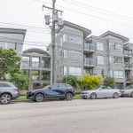 Contemporary multi-family residential building with modern architecture, large windows, and balconies, located in a vibrant urban neighbourhood.