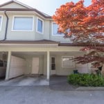 Spacious two-story townhouse with covered parking, lush landscaping, and a vibrant red maple tree, offered by Orca Realty Inc., ideal for Vancouver Island residential real estate.