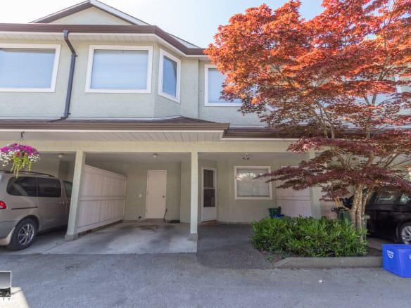 Spacious two-story townhouse with covered parking, lush landscaping, and a vibrant red maple tree, offered by Orca Realty Inc., ideal for Vancouver Island residential real estate.