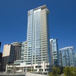 Modern high-rise residential building in Vancouver skyline, showcasing luxury apartments with glass facades for urban living.