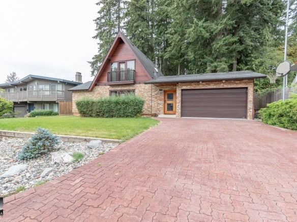 Modern residential home with brick and wood exterior, landscaped yard, and paved driveway in Vancouver, BC.