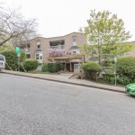 Modern residential apartment building with lush landscaping and ample parking in Vancouver, BC. Features balconies, well-maintained gardens, and prime location for urban living. Ideal for families and professionals.