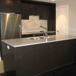 Modern black kitchen with stainless steel appliances and a white countertop island, featuring a sleek design and contemporary finishes, perfect for Vancouver real estate listings.