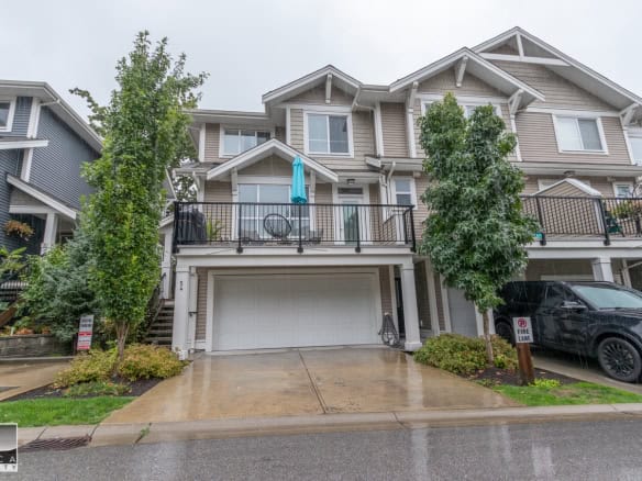 Spacious multi-level townhouse with garage and balcony, modern design, located in a desirable neighbourhood with lush landscaping and rain-friendly driveway, ideal for Vancouver real estate buyers.