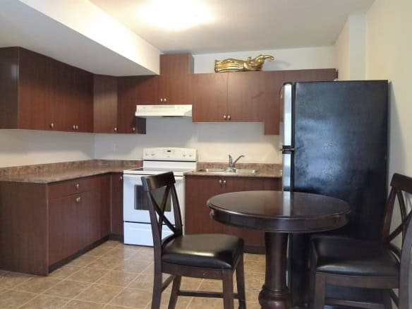Modern kitchen with dark wood cabinets, white appliances, and a cozy dining area, ideal for home cooking and entertaining, situated in a family-friendly residential property on Orca Realty Inc. listings.