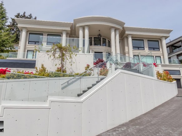 Luxurious modern waterfront mansion with grand architecture, elegant columns, and expansive glass railings, showcasing high-end real estate in Vancouver, BC.
