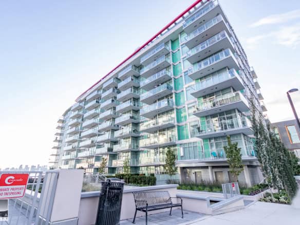 Modern multi-story residential condo building with glass balconies, located in Vancouver, Canada, showcasing contemporary urban real estate options by Orca Realty Inc.