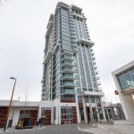 Contemporary high-rise residential building in Vancouver with modern architecture, glass balconies, and surrounding visitor parking area, showcasing Orca Realty Inc.'s property offerings.