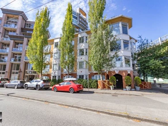 Modern multi-story residential building in Vancouver with contemporary architecture, large windows, and surrounding greenery. Perfect for real estate investments and buying condos in BC.