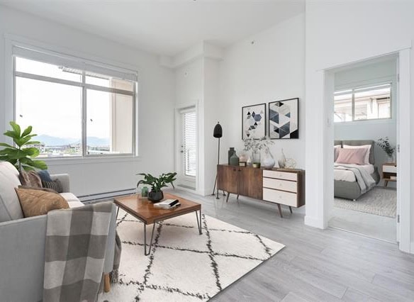 Bright and modern living room interior with large window, stylish decor, and a cozy bedroom in the background, showcasing Vancouver real estate properties.
