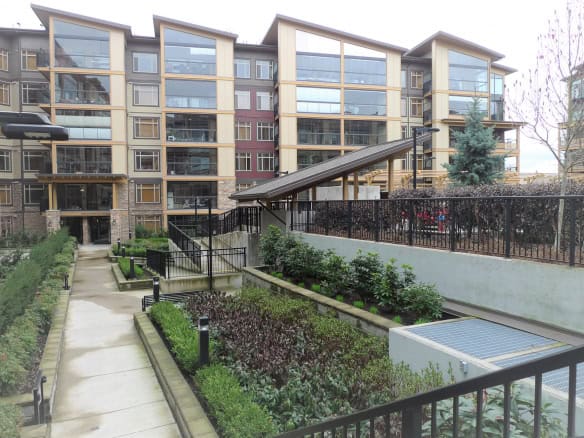 Modern multi-story residential complex with landscaped gardens and outdoor amenities in Vancouver's real estate market.