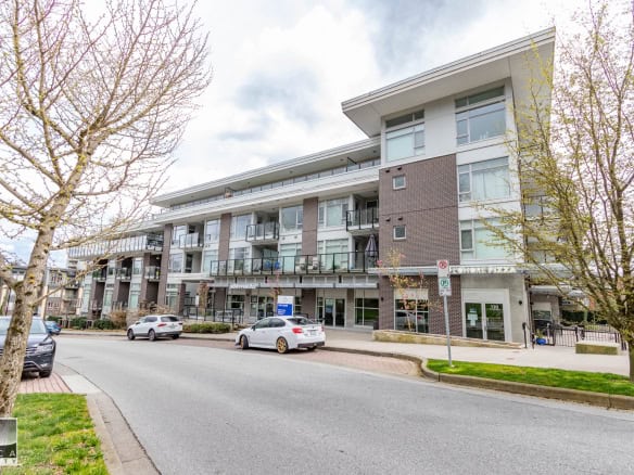 Modern multi-story residential building with balconies, located in a vibrant neighbourhood with parking and green spaces, ideal for Vancouver real estate investments.
