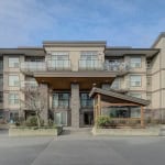 Modern multi-unit residential building with contemporary design and spacious balconies, featuring stone accents and a landscaped entrance, perfect for Vancouver real estate investment or living.