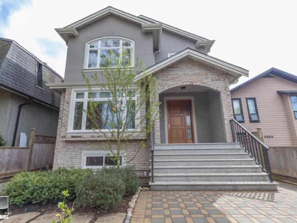 Modern Vancouver home with stone and stucco exterior, inviting front porch, landscaped yard, and staircase, ideal for buyers seeking contemporary architecture in a prime neighbourhood.