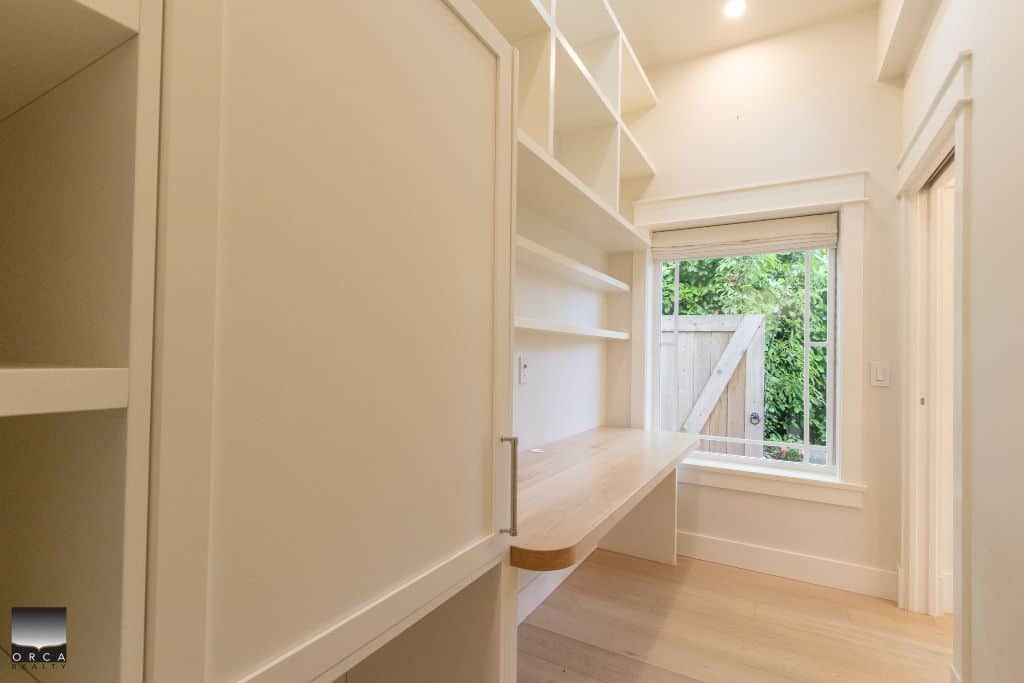 Spacious white built-in home office with large window overlooking green backyard, ideal for modern Vancouver real estate and residential property listings.