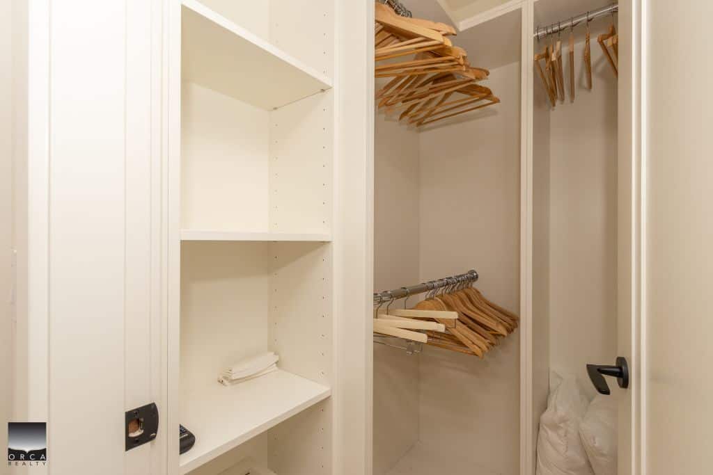 White walk-in closet with wooden hangers and shelf storage, ideal for home organization and real estate staging.