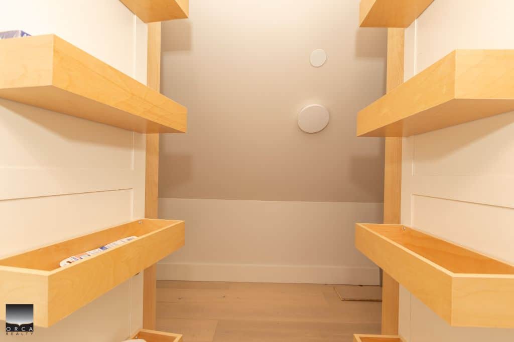 Spacious walk-in closet with wooden shelves, ideal for organized storage and home organization solutions. Perfect for showcasing real estate or interior design features.