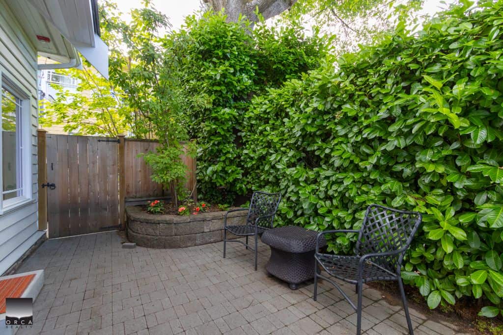 Lush backyard patio area with garden beds, greenery, and outdoor seating, perfect for relaxing or entertaining in a Vancouver property listed by Orca Realty Inc.