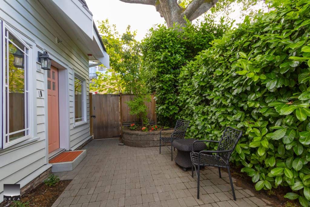 Garden patio area with seating and lush greenery in a residential backyard, showcasing outdoor living space maintained by Orca Realty Inc. in Vancouver BC.
