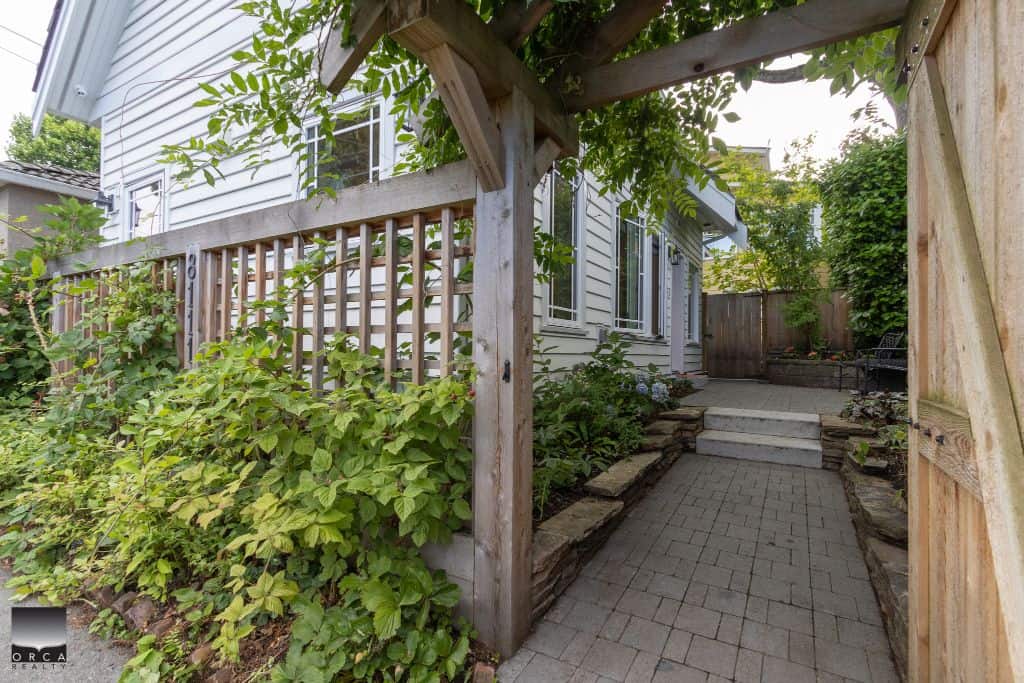 Lush garden pathway leading to a cozy backyard patio at Orca Realty Inc. listed property, featuring stone steps, greenery, and a private outdoor space, ideal for Vancouver Island real estate buyers.