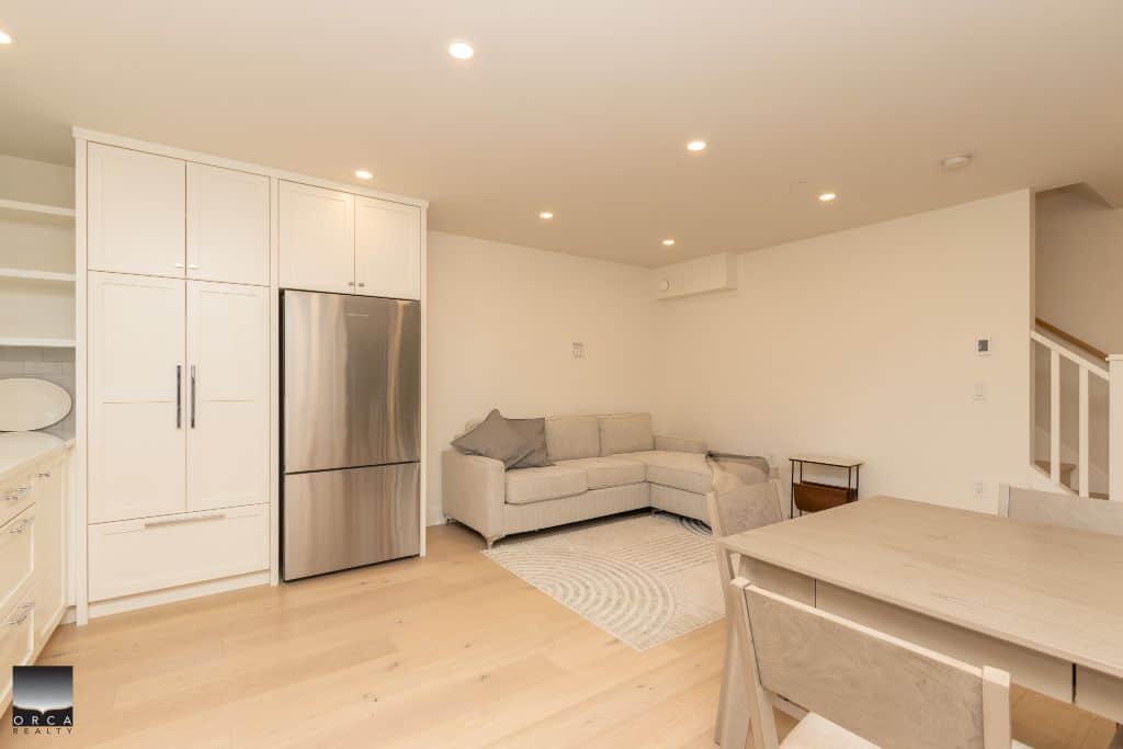 Modern open-concept living space with kitchen, dining, and living area, featuring neutral tones, natural light, and contemporary furnishings, ideal for Vancouver homebuyers.