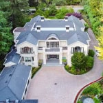 Luxurious modern mansion with elegant architecture, surrounded by lush greenery, available for sale through Orca Realty Inc. in Canada.