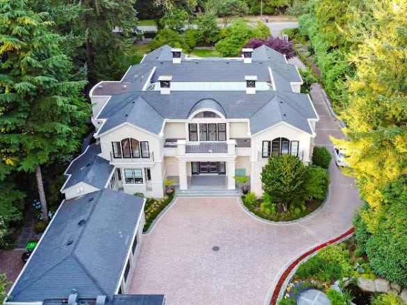Luxurious modern mansion with elegant architecture, surrounded by lush greenery, available for sale through Orca Realty Inc. in Canada.