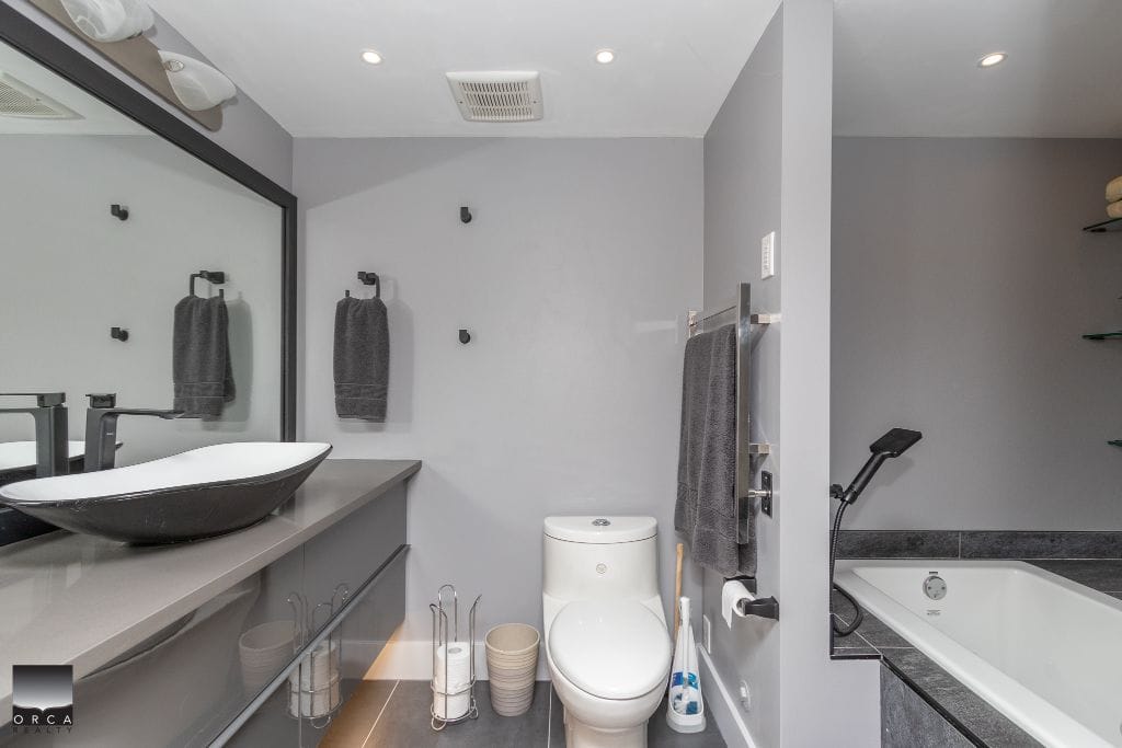 Modern grey bathroom with vessel sink, walk-in shower, and bathtub, featuring contemporary fixtures and towels. Perfect for showcasing Vancouver Island luxury real estate with Orca Realty Inc.