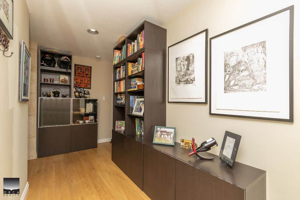 Modern interior home decor with a dark wood bookshelf, framed artwork, and decorative items - Orca Realty Inc. real estate agent services.