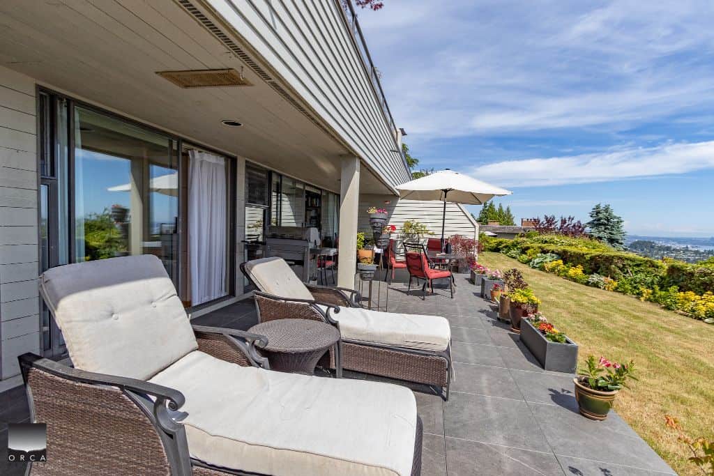 Spacious outdoor patio with lounge chairs, dining area, and scenic city views, perfect for relaxing or entertaining in a luxury home listed by Orca Realty Inc. in Vancouver.