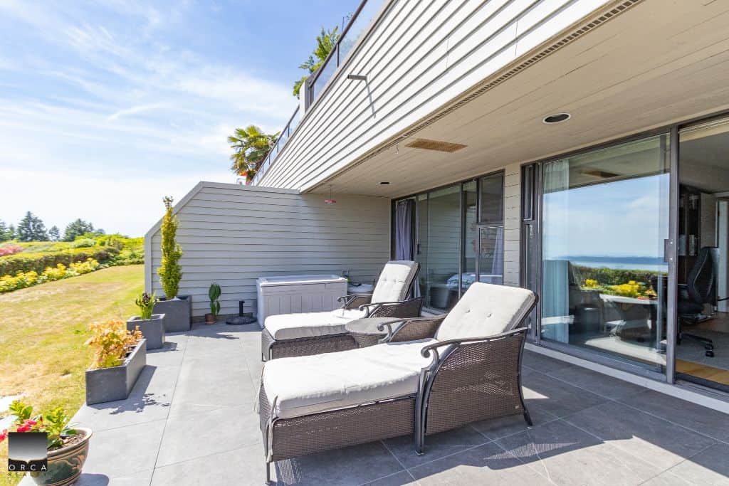 Modern condo balcony with lounge chairs, overlooking scenic ocean and landscape views, perfect for relaxing and enjoying the outdoors in British Columbia.