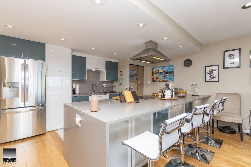 Spacious modern kitchen in an Orca Realty Inc. listing with elegant cabinetry, stainless steel appliances, and a large island for cooking and entertaining. Perfect for Vancouver Island homebuyers.