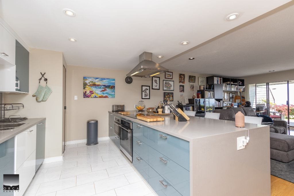 Modern kitchen with grey and white cabinetry, open concept living space, stylish decor, and natural light, ideal for Vancouver Island homebuyers seeking a contemporary residence.