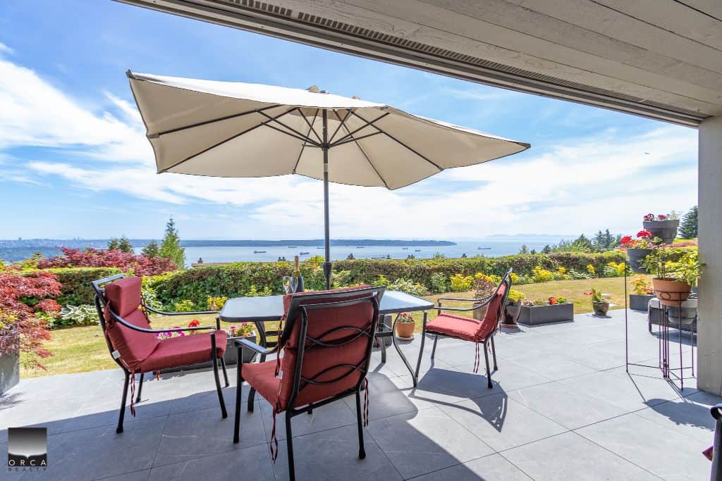 Stunning outdoor patio with panoramic water views, vibrant flowers, and comfortable seating, perfect for relaxing or entertaining in B.C. waterfront real estate.