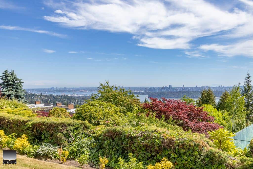 Panoramic view of Vancouver skyline and lush garden landscape from Orca Realty property, showcasing stunning natural surroundings.