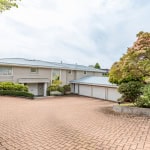 Spacious driveway leading to a modern residential home with landscaped gardens and mature trees, showcasing professional real estate services by Orca Realty Inc. in Victoria, BC.
