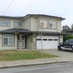 Contemporary two-storey house in a suburban neighbourhood with modern design, large windows, and attached garage, featuring Orca Realty vehicle parked in front.