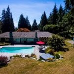 Elegant single-family home with a backyard pool surrounded by lush trees, perfect for outdoor living and privacy, offered by Orca Realty Inc.