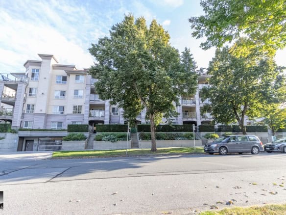 Modern multi-unit residential building with lush trees and well-maintained surroundings in Vancouver, BC, ideal for real estate investment and property management in the local market.