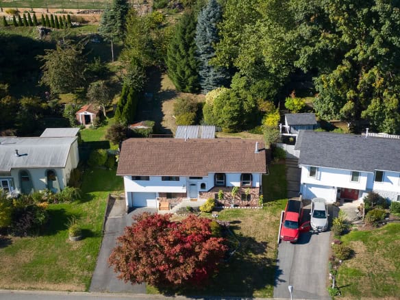 Bright aerial view of a family home with a lush backyard, trees, and neighboring houses, perfect for real estate listing in Vancouver and showcasing residential properties by Orca Realty Inc.