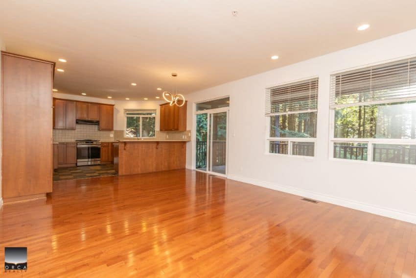 Bright open-concept living space with hardwood floors, large windows, and modern kitchen, ideal for comfortable family living and entertaining in Victoria, BC.