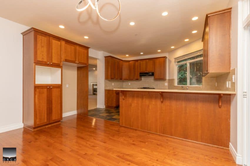 Spacious kitchen with wooden cabinets, breakfast bar, and modern appliances in a family home, featuring hardwood flooring and large window for natural light, offered by Orca Realty Inc.