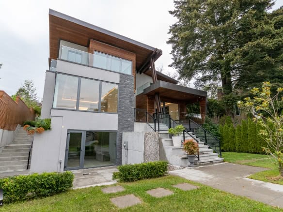 Modern luxury home with large glass windows, elegant wood accents, landscaped yard, and spacious balconies, located in a desirable neighbourhood. Perfect for upscale residential living.