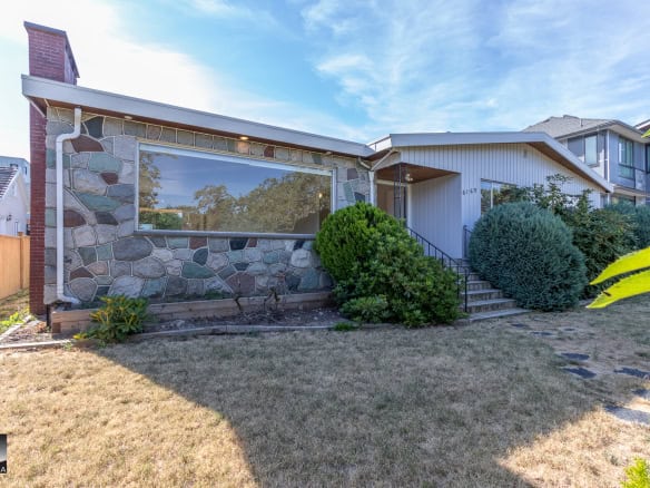 Charming mid-century modern house with stone accent wall, manicured front yard, and vibrant green shrubs, located in a desirable neighbourhood in Vancouver.