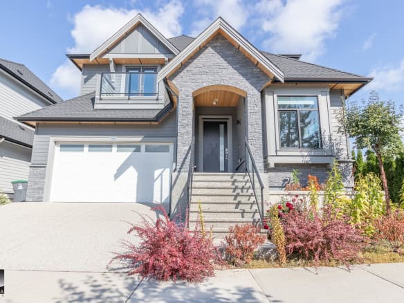 Modern Vancouver-style house with stone facade and large windows, perfect for family living; situated in a desirable neighbourhood with easy access to amenities and outdoor spaces.
