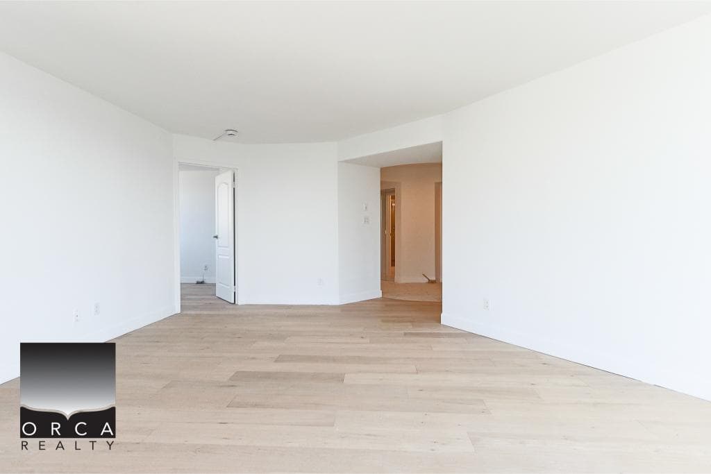 Bright empty living room with white walls, natural light, and light wood flooring, showcasing modern home interior design for Vancouver real estate listings.