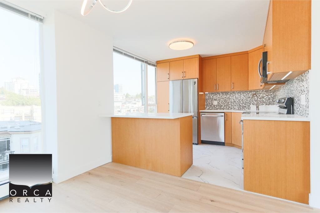 Bright modern kitchen with stainless steel appliances, wood cabinetry, and a stylish backsplash, perfect for Vancouver condo living.